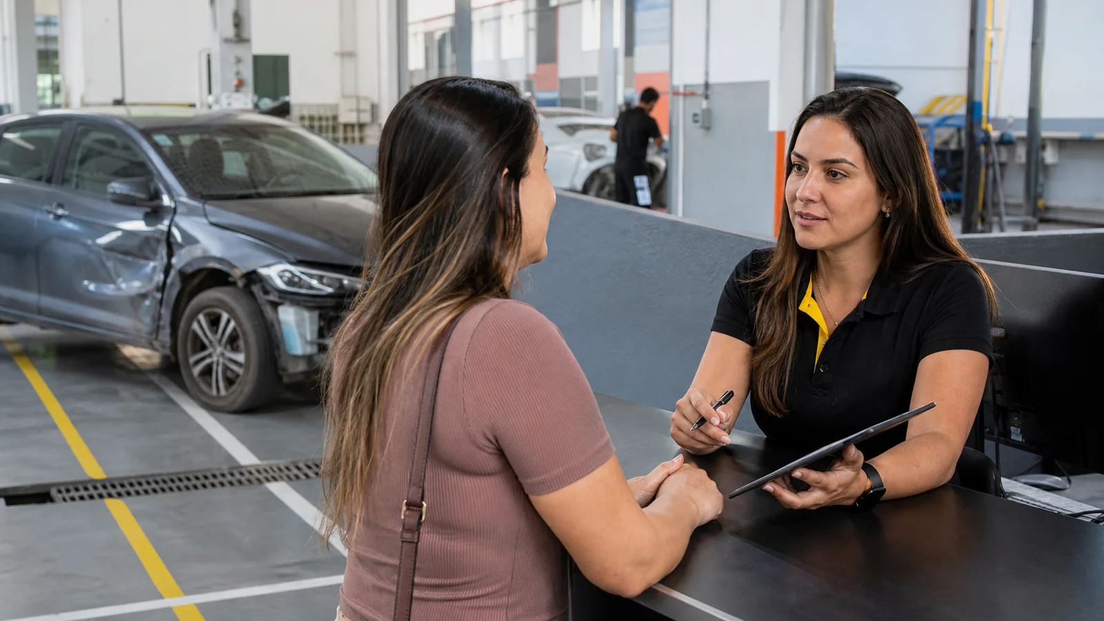 Consultora de oficina orientando uma cliente sobre o atendimento do seguro automotivo