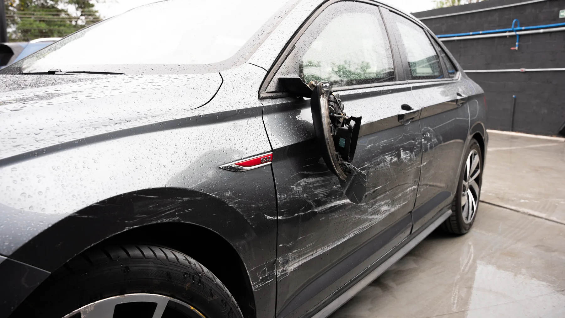 Carro com retrovisor quebrado e danos na lateral após uma colisão